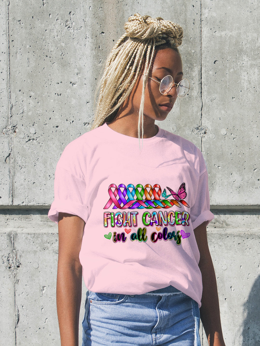 Person wearing a pink t-shirt with colorful text and graphics against a concrete wall.
