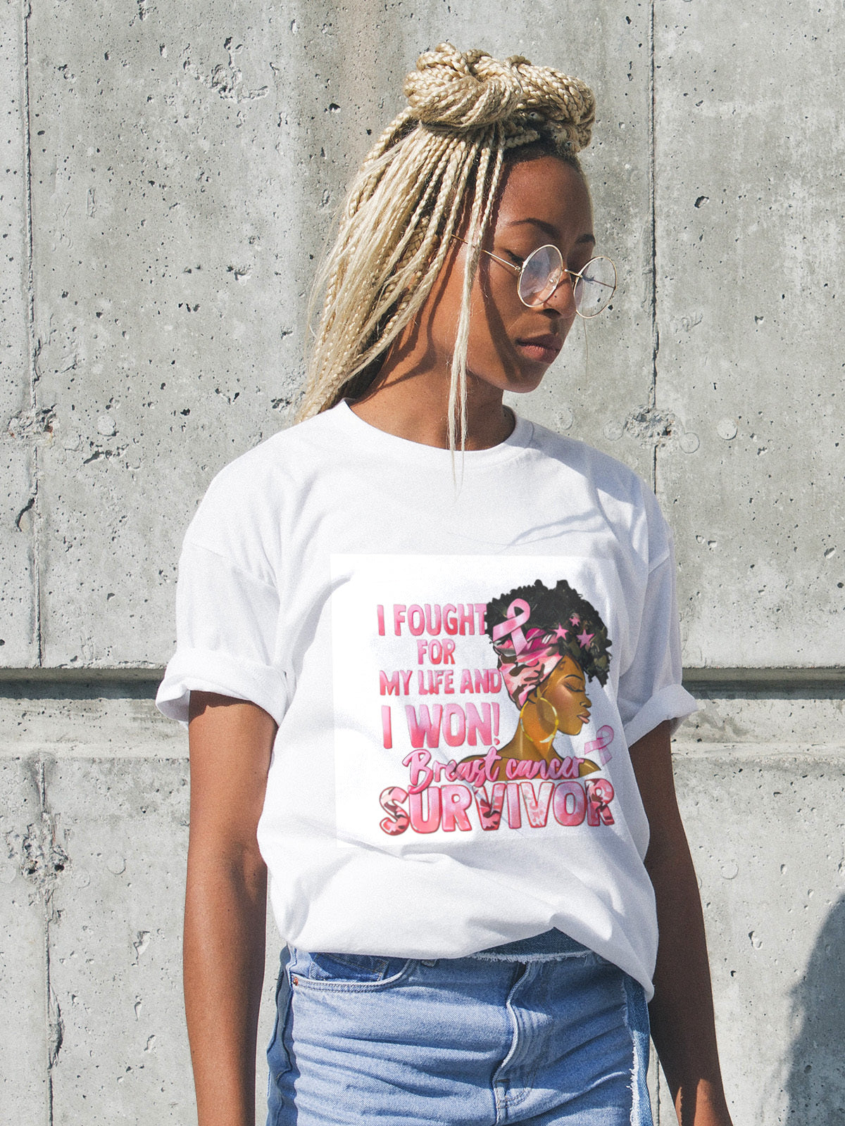 Woman wearing a white t-shirt with a graphic and text, standing against a concrete wall.