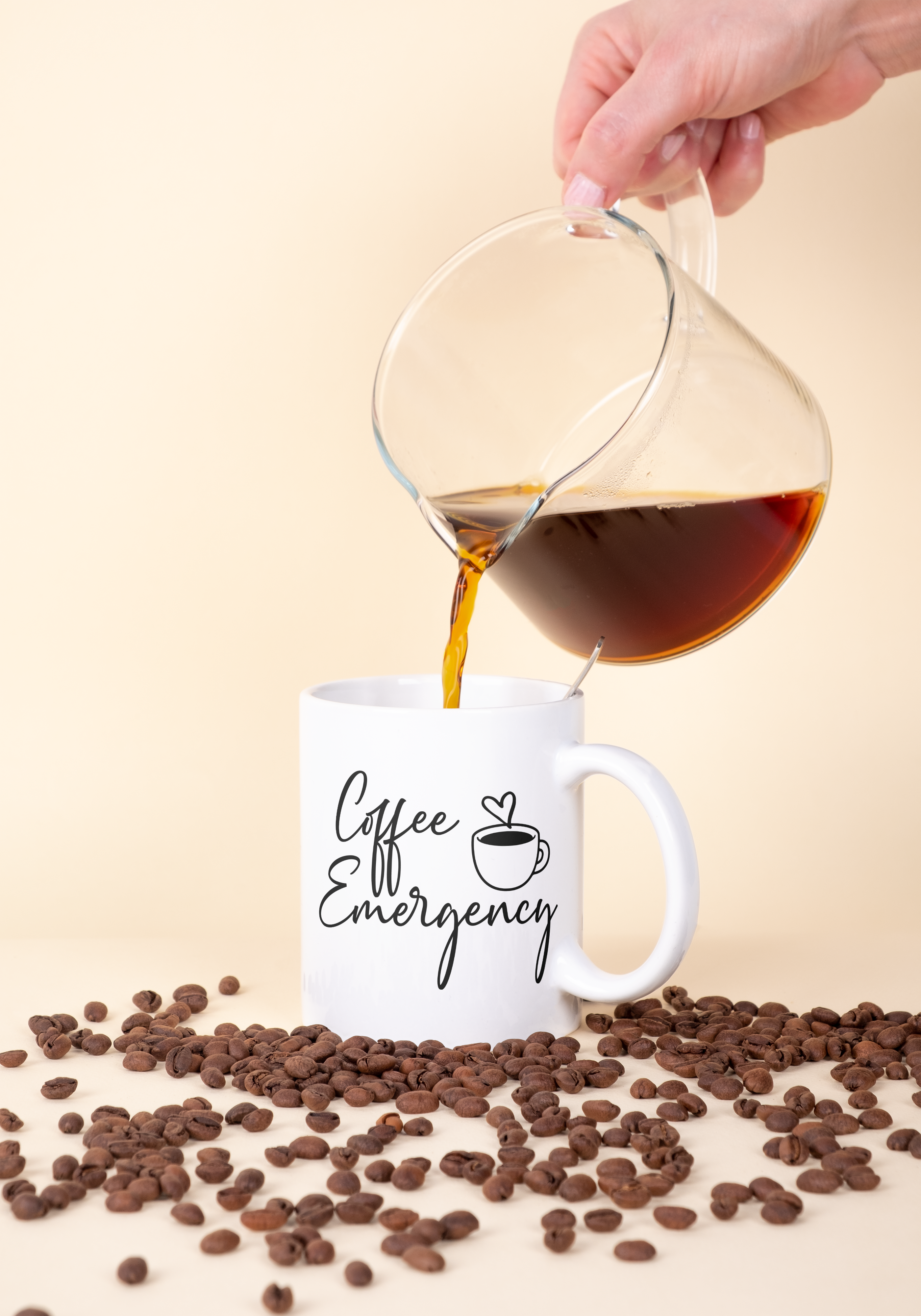 Person pouring coffee from a carafe into a mug with 'Coffee Emergency' text, surrounded by coffee beans on a beige background.